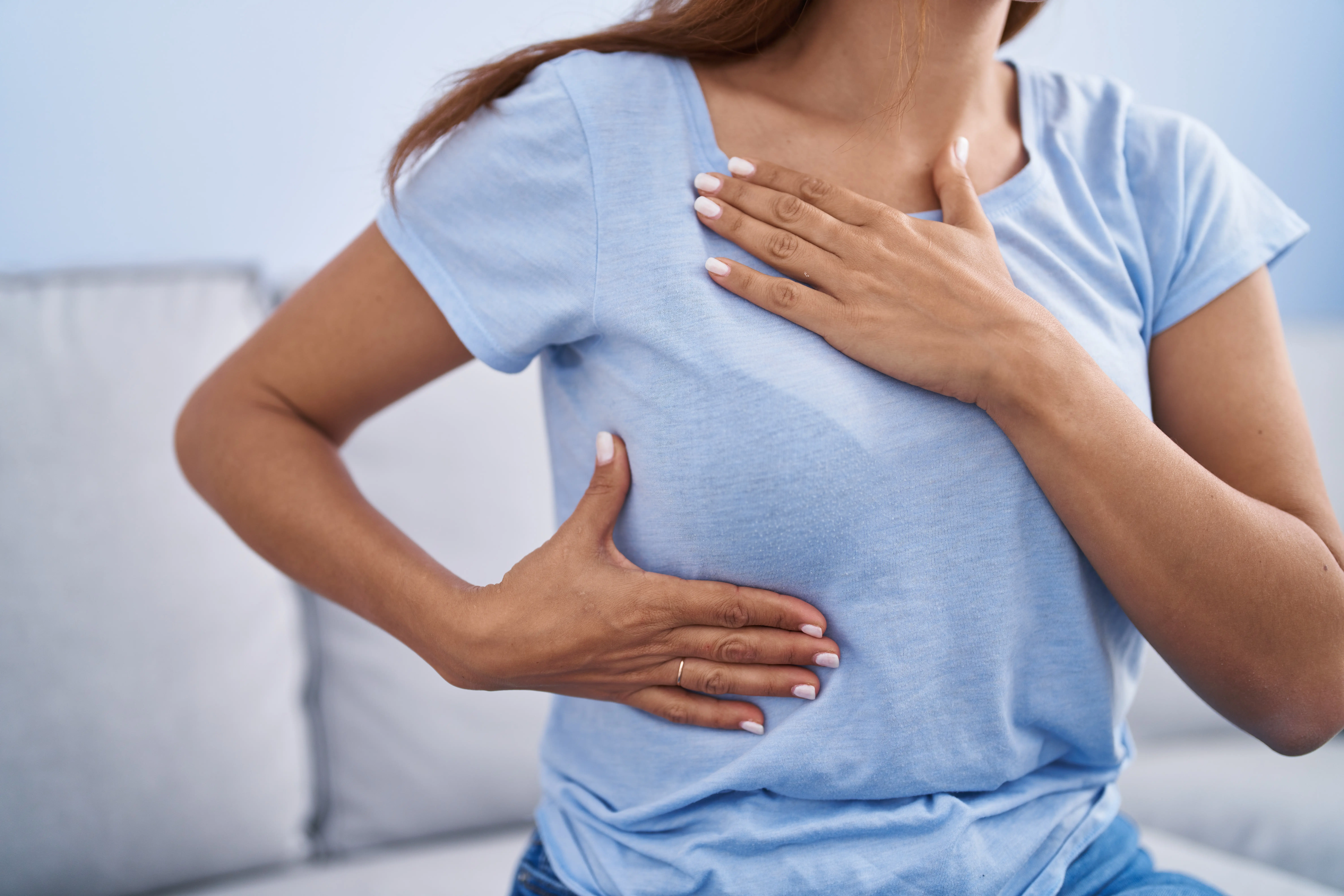 Faceless mother holding swollen breast